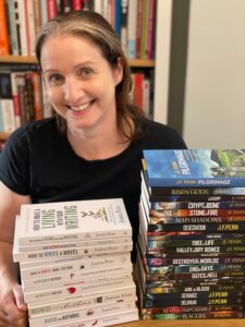 Joanna Penn behind two stacks of books that she's authored in both fiction and non-fiction.